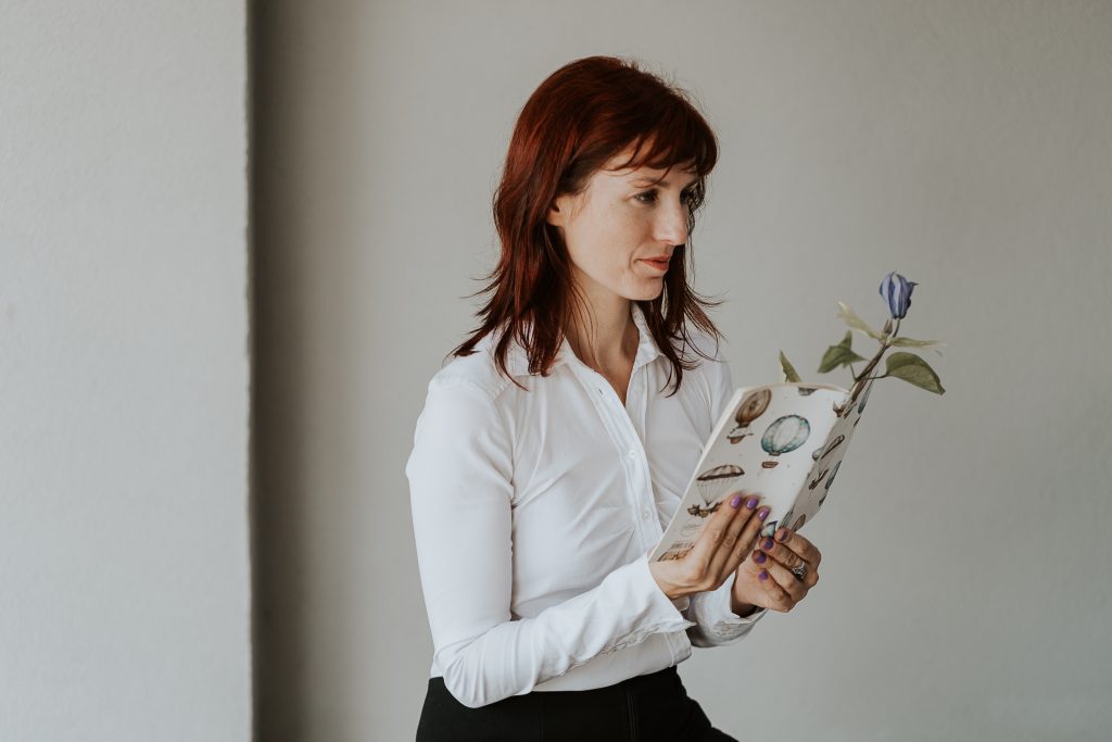 Autrice che legge un quaderno da cui spunta un fiore